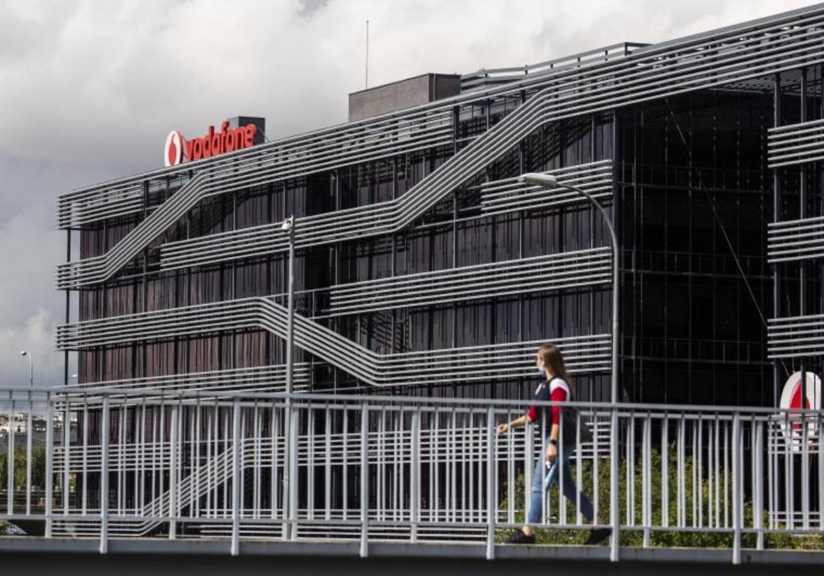 Una persona camina al lado de la sede de Vodafone en Madrid.