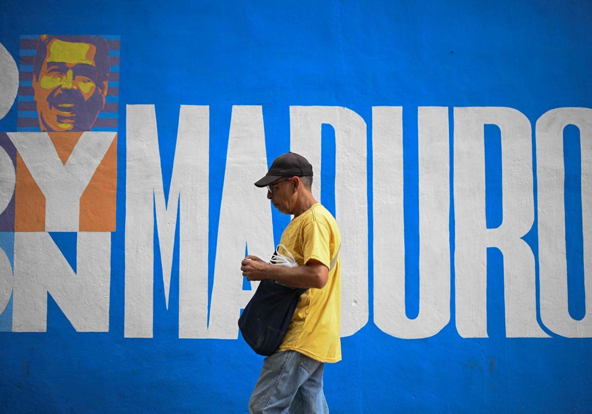 Un hombre pasa junto a un mural de campaña del presidente Nicolás Maduro en Caracas.