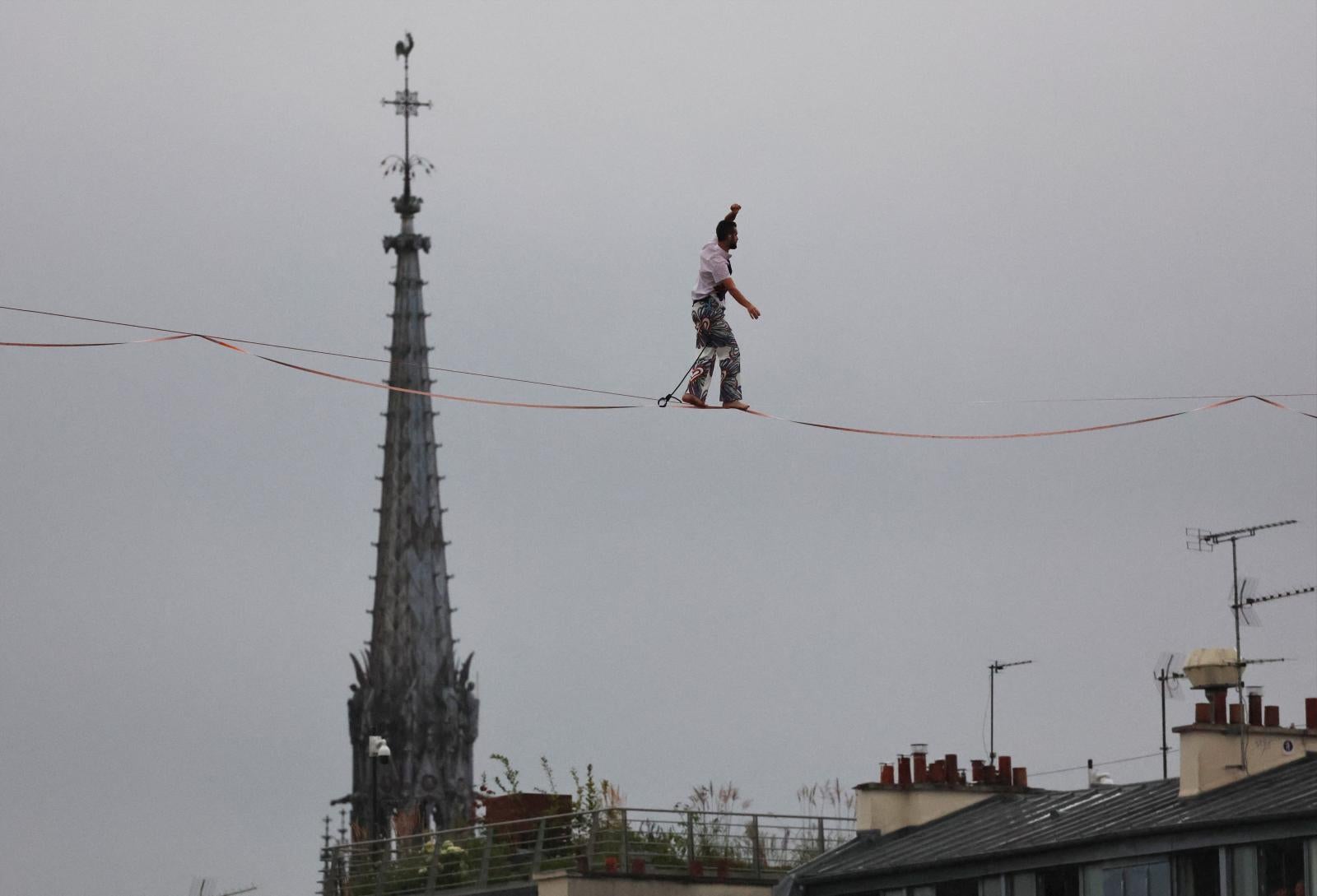 Un artista camina sobre una cuerda floja sobre el río Sena durante la ceremonia de apertura.