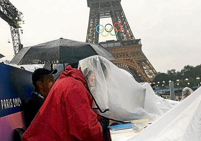 Los periodistas, trabajando bajo la lluvia.