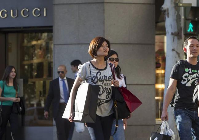 Unos ciudadanos chinos salen de la tienda Gucci en Madrid tras hacer unas compras.