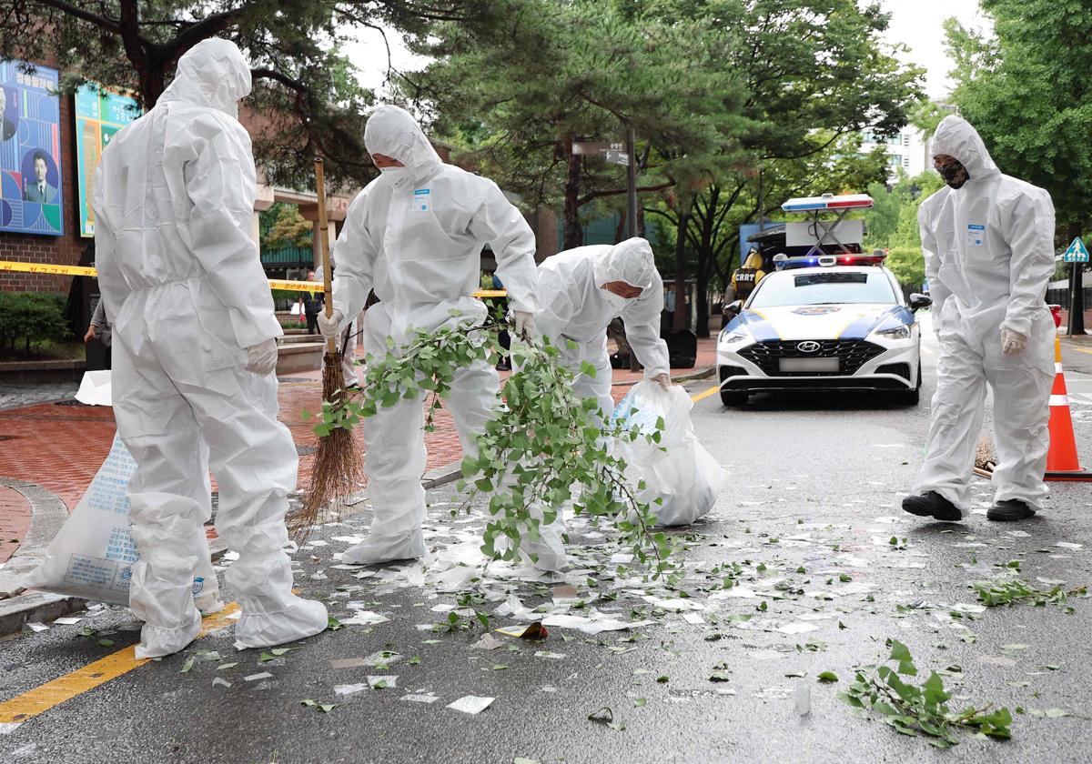 Barrenderos con traje de protección para guerra química y biológica recogiendo basura norcoreana en Corea del Sur.