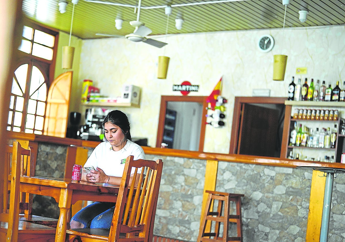 Imagen principal - De arriba a abajo: Una mujer toma un refresco en el bar de Jairo, el único de Bayubas de Abajo, un pueblo de Soria de 150 lugareños. Vecinos de Bayubas charlan a las puertas de la taberna. Yolanda, en su bar de San Cebrián de Mazote, otro pequeño pueblo de cien habitantes en Valladolid. 