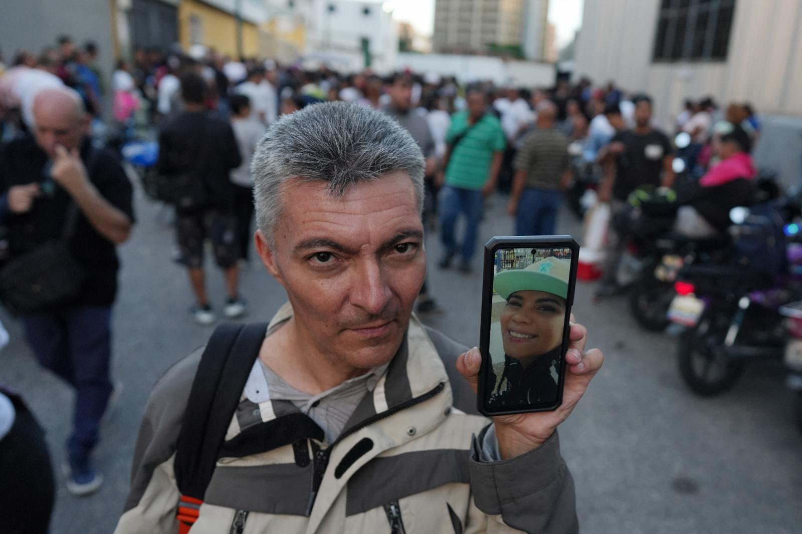 Un hombe muestra una foto de su mujer, detenida en una protesta antichavista.