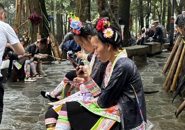 Jóvenes ataviadas con el traje miao consultan el móvil.