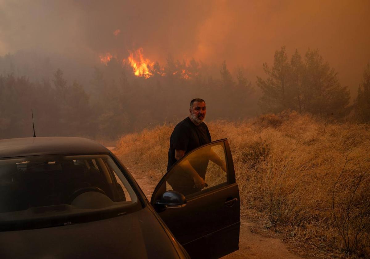 Un vecino se sube a su coche frente a las llamas para evacuar a los habitantes de Dione.