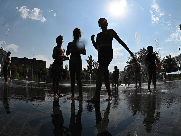 Niños se refrescan en una fuente durante una ola de calor.