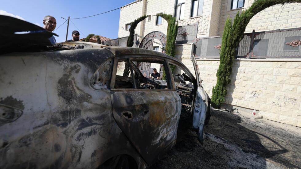 Varios palestinos observan un coche calcinado durante el asalto a la población cisjordana de Jit.