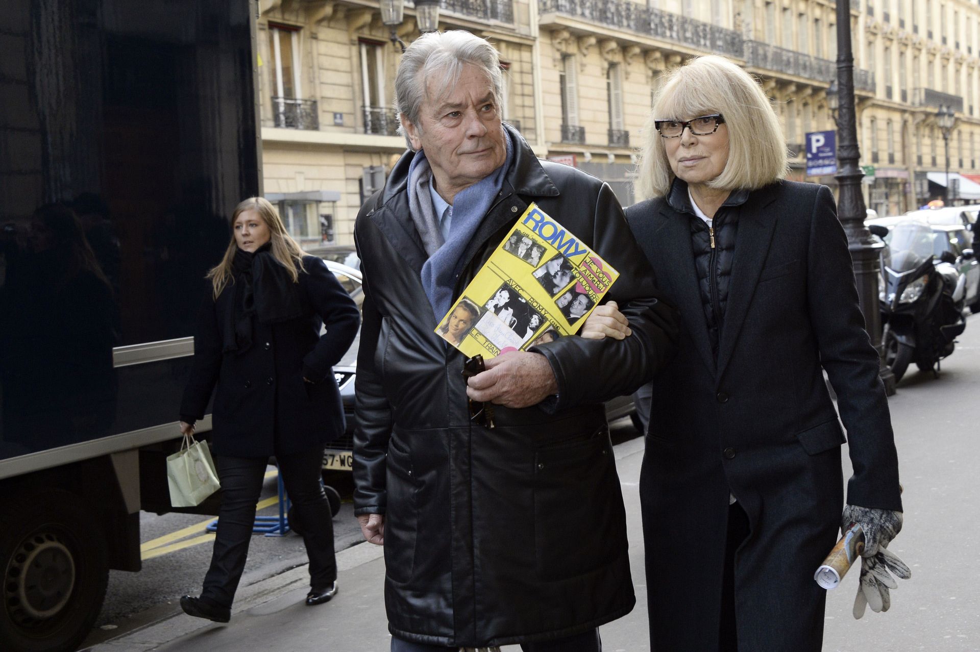 Alain Delin y su exmujer Mireille Darc caminan del brazo por una calle de París tras asistir a un funeral en París en 2013.