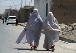 Dos mujeres con el cuerpo completamente cubierto caminan por una calle de Kandahar, en Afganistán.