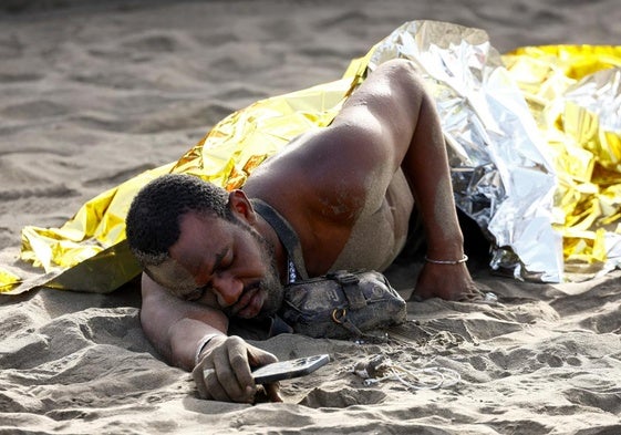 Un migrante descansa en una playa canaria tras haber completado su travesía.