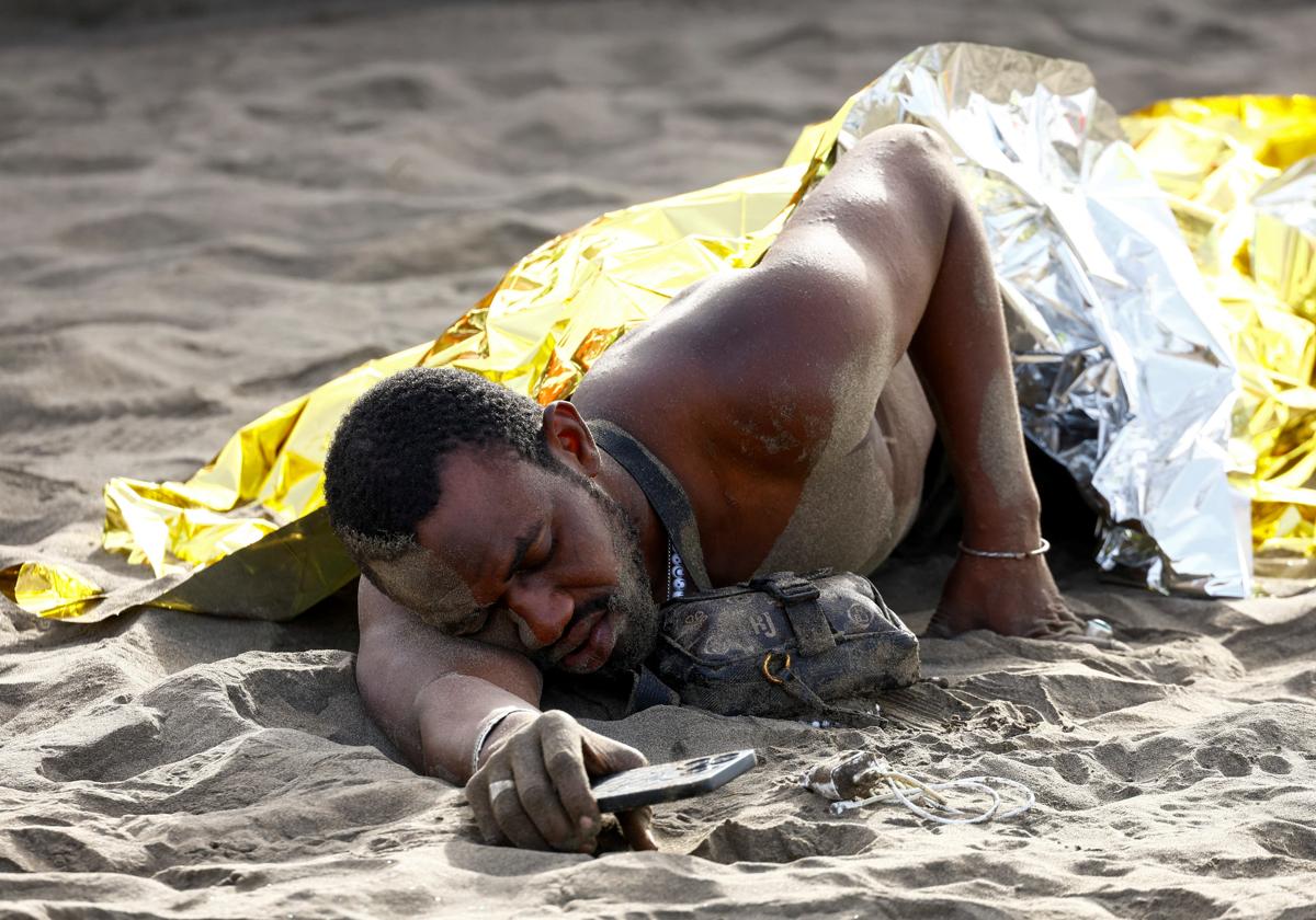 Un migrante descansa en una playa canaria tras haber completado su travesía.