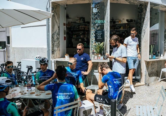 Los ciclistas del Decathlon, relajados tomando algo en una terraza con Ben O'Connor en primer plano, de espaldas.