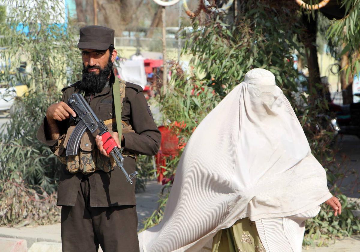 Una mujer pasa por delante de un puesto de control de los talibanes afganos en Kandahar.