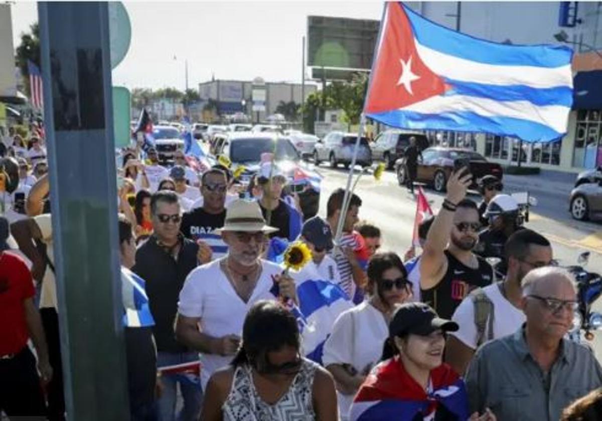 Votantes latinos exhiben banderas cubanas y estadonidenses en una calle de Florida.