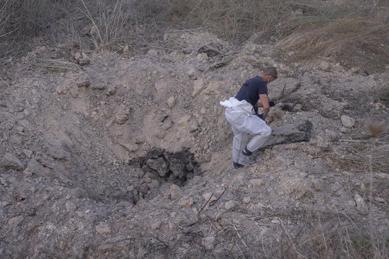 Una experta en explosivos busca restos del misil en el cráter dejado por la explosión.