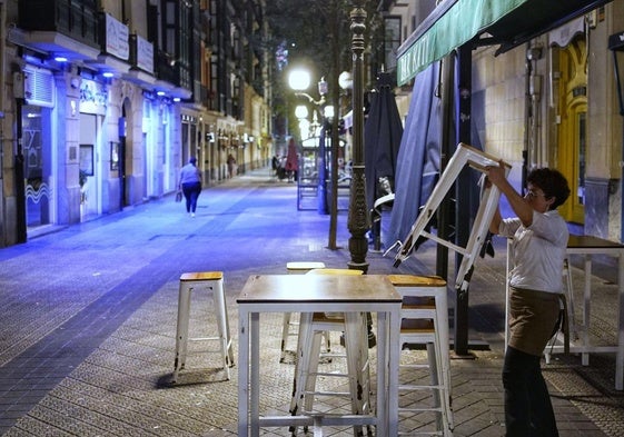 Un camarero recoge la terraza de un bar de Bilbao.