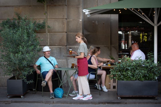 Camarera sirviendo bebida en una terraza en Barcelona.