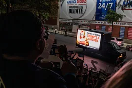 Ambiente en el exterior de los estudios de la CBS en Nueva York, con periodistas, curiosos y una crítica incluida a Trump en un camión.