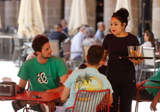 Una trabajadora de hostelería atiende a unos clientes.