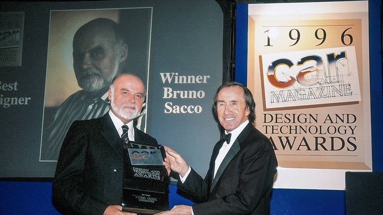 El tricampeón del mundo de F1, Sir Jackie Stewart, entrega a Sacco el premio de «Mejor diseñador» de la revista «Car», en 1996