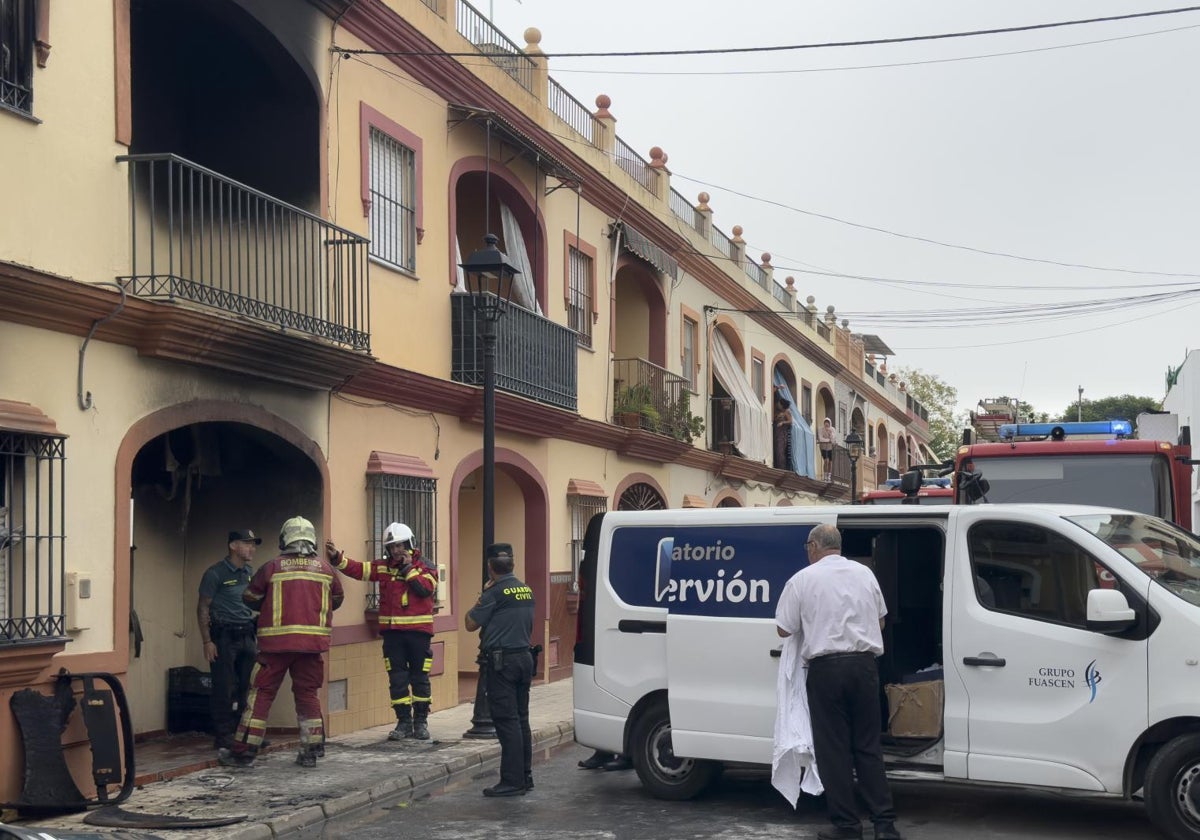 Bomberos y guardias civiles ante la entrada de la casa incendiada en Guillena (Sevilla) el pasado domingo.