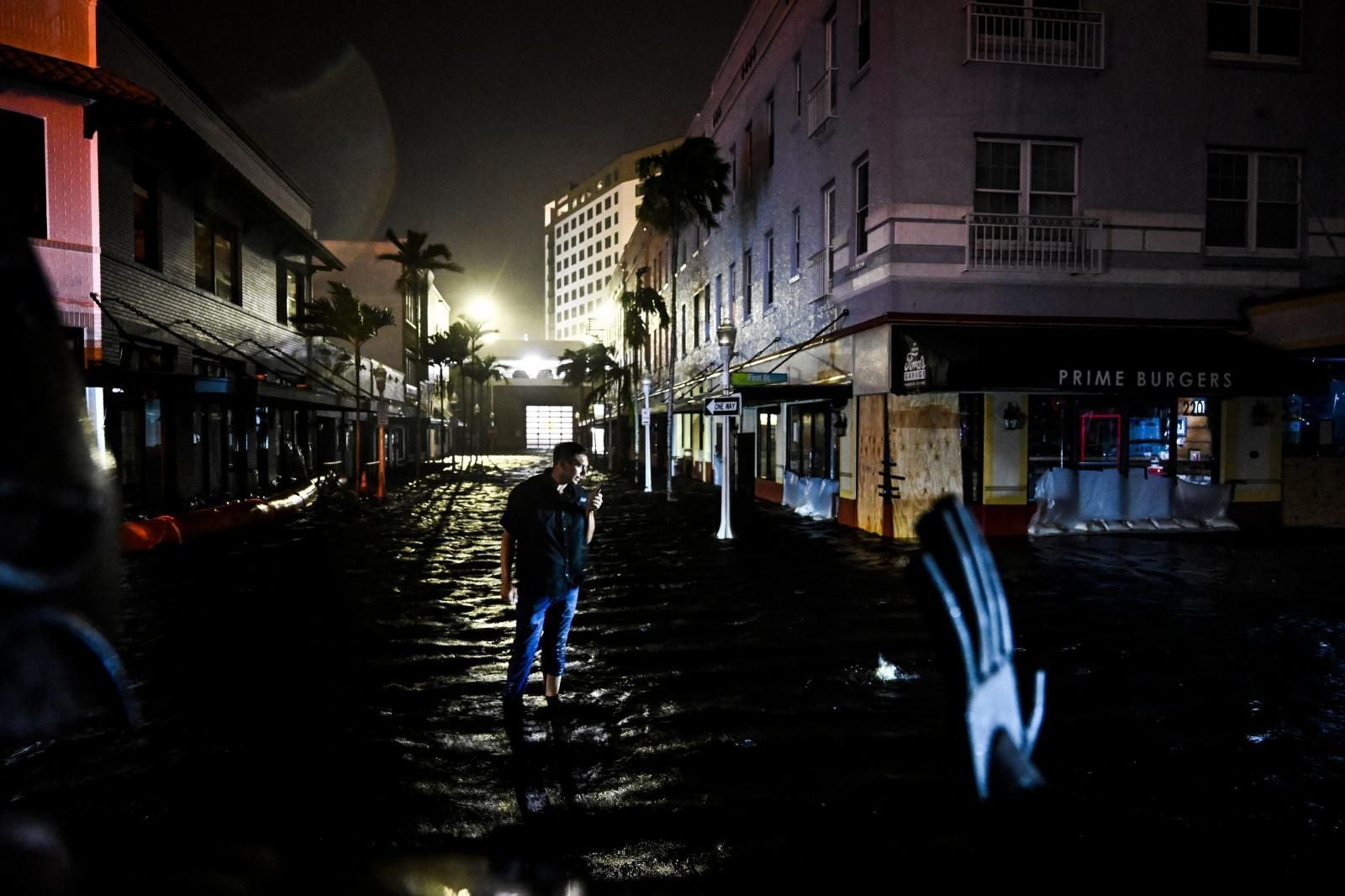 Un hombre habla por teléfono mientras camina por calles inundadas de agua después de que el huracán Milton tocara tierra en Fort Myers, Florida, el 9 de octubre de 2024.