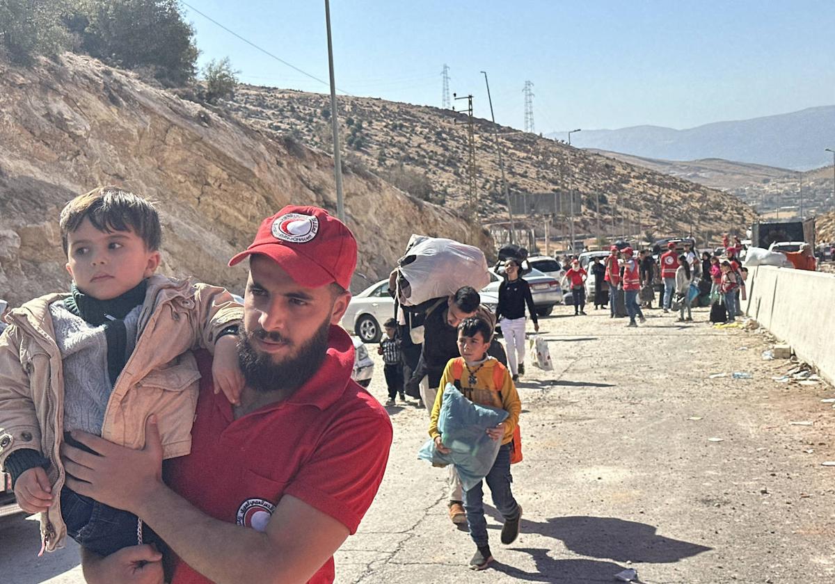 Miembros de la Media Luna Roja ayudan a las familias a cruzar el paso fronterizo de Al-Masnaa.