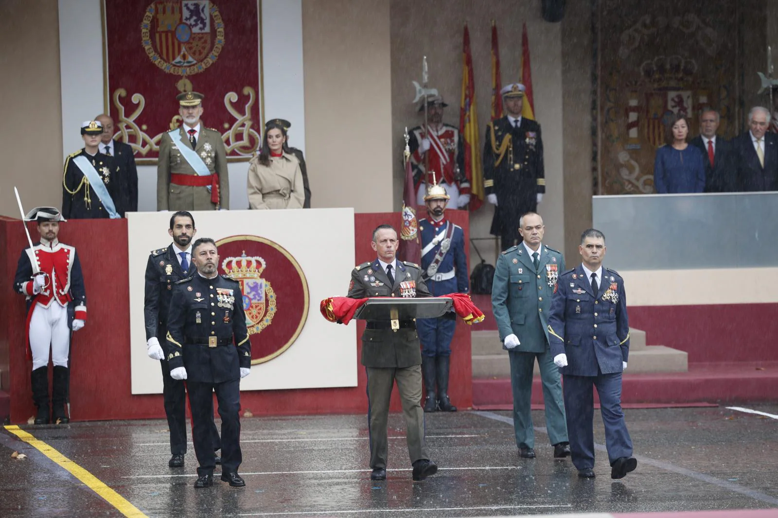 Representantes de los tres ejércitos, de la Policía Nacional y de la Guardia Civil, portan la bandera de España ante el rey Felipe VI, la reina Letizia, y la princesa de Asturias, Leonor de Borbón,este sábado, durante el tradicional desfile del Día de la Fiesta Nacional.