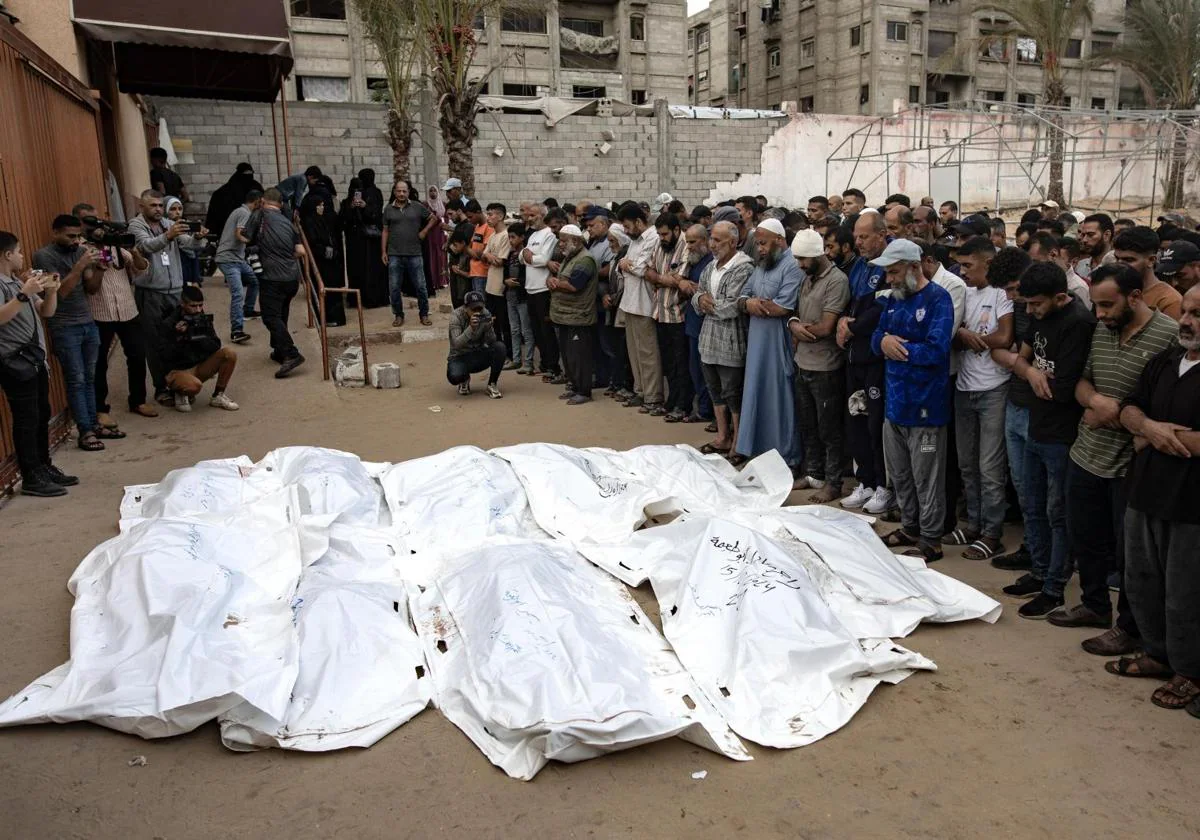 Palestinos rezan junto a los cadáveres de los miembros de la familia AbúTaima, muertos en un ataque aéreo israelí, en el campo de refugiados de Jan Younis.