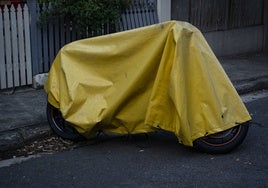 Moto en la carretera con funda impermeable.