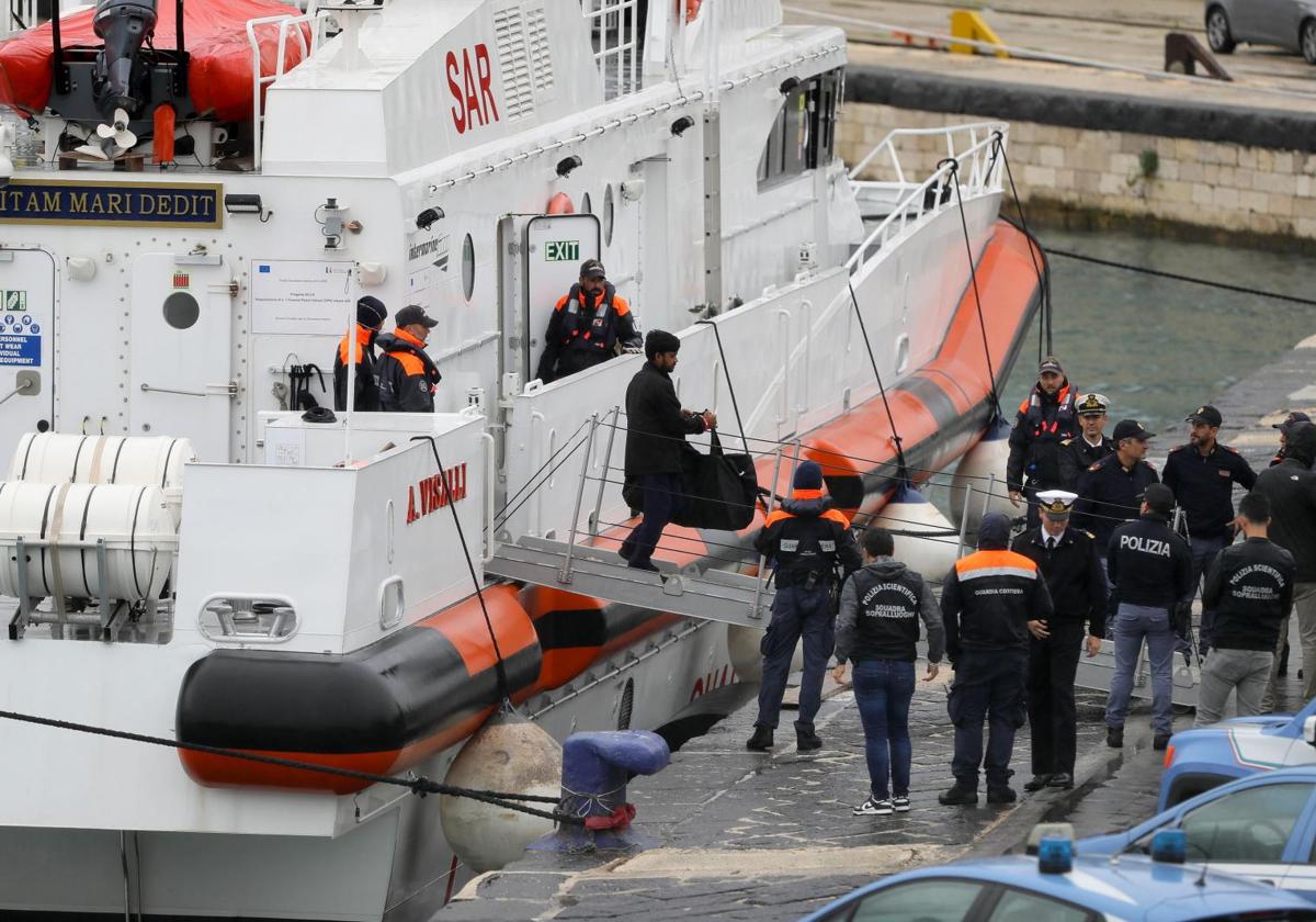 Uno de los migrantes devueltos a Italia desembarca en Bari de la patrullera de la guardia costera.