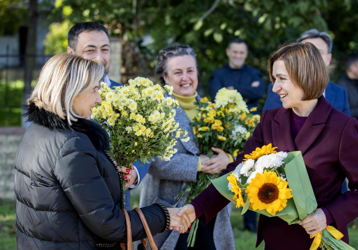 Una simpatizante estrecha la mano a la actual presidenta moldava, Maia Sandu, favorita en las encuestas.