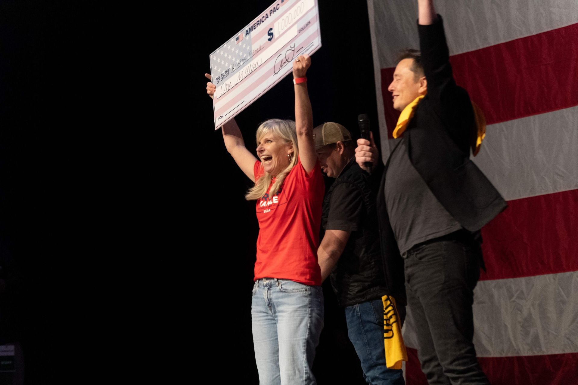 Elon Musk entrega el cheque de un millón de dólares del domingo a la ganadora Kristine Fishell en un mitin en Pittsburgh (Pensilvania).