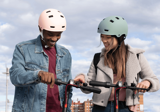 Chico y chica en monopatines eléctricos con casco .