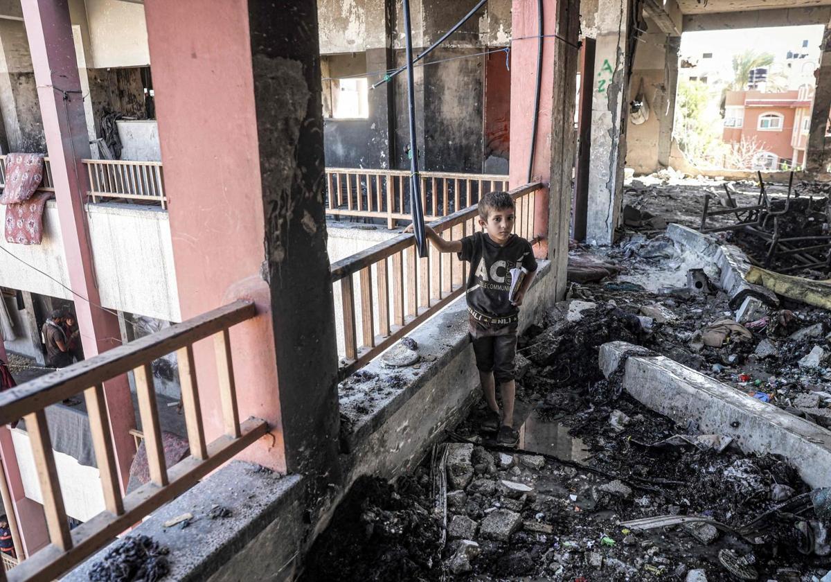 Un niño camina entre los escombros de la escuela gazatí de Nuseirat atacada por las tropas hebreas.