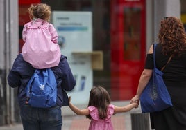 Unos padres acompañan a sus hijas al colegio.