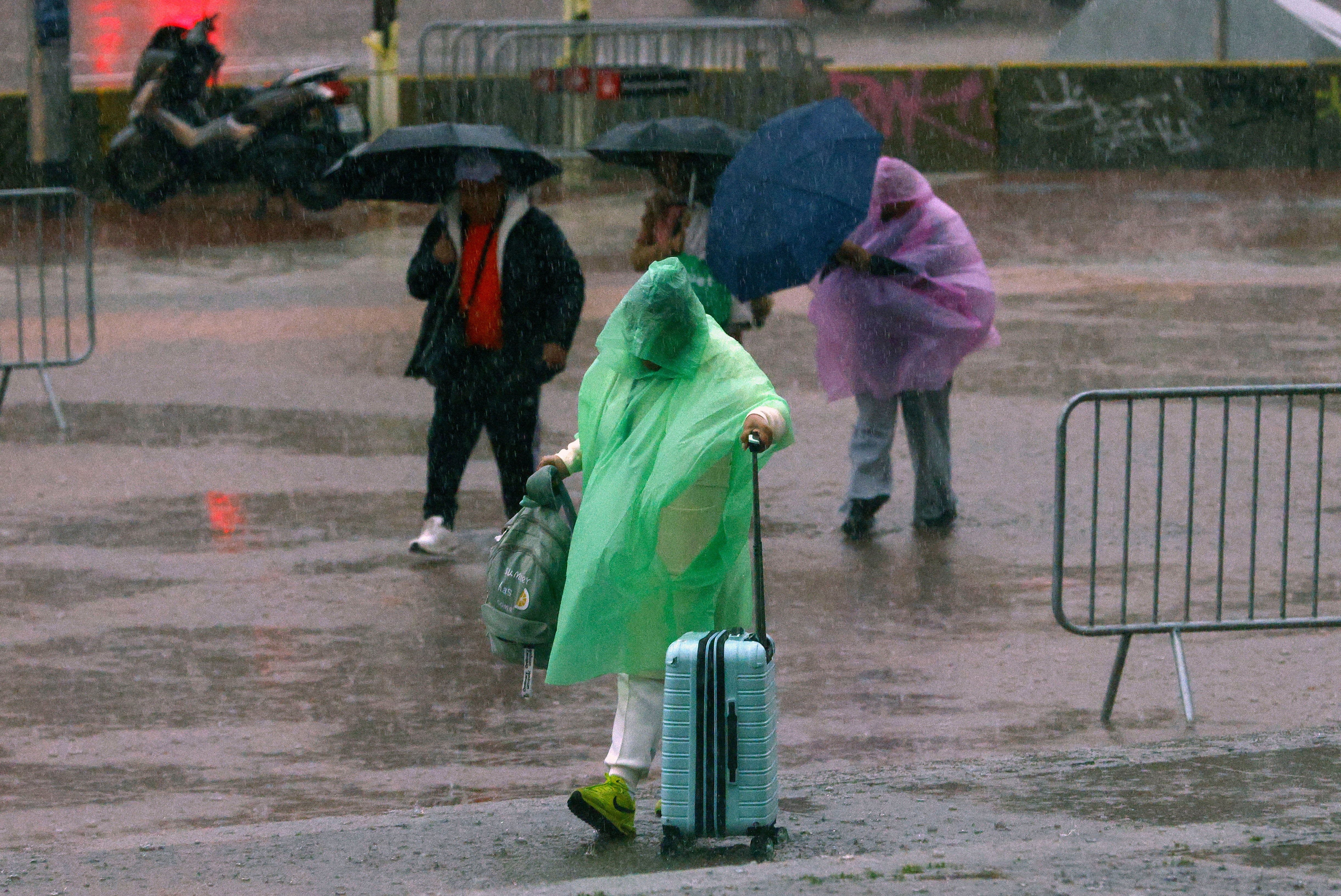 Varias personas se protegen de la lluvia en la Plaza de Espanya de Barcelona este lunes 