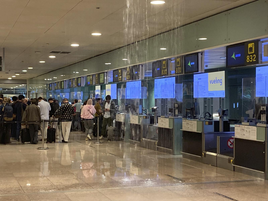 Varias personas en el aeropuerto de Barcelona-El Prat este lunes al lado de las goteras.