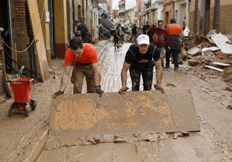 Vecinos afectados por la dana retiran las ingentes cantidades de barro acumuladas en las calles de Paiporta.