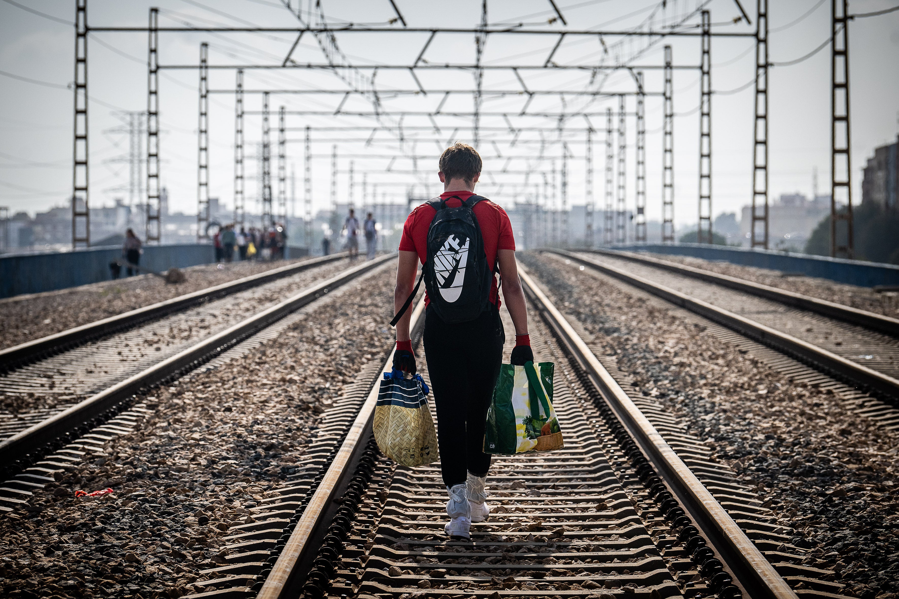 Un hombre camina con provisiones por las vías del tren en La Torre