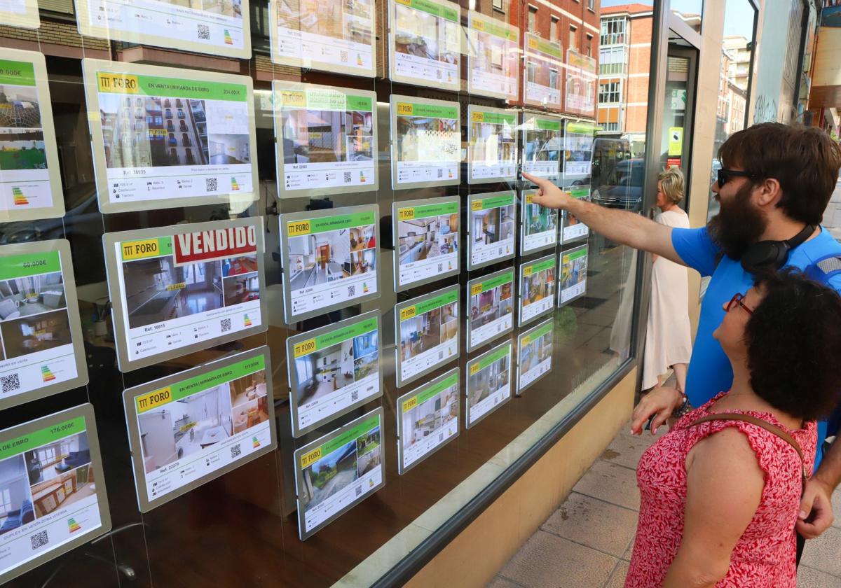 Una pareja mirando un escaparate de una inmobiliaria.