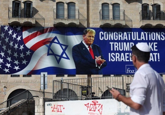 Un hombre camina junto a un cartel instalado en Jerusalén para felicitar la victoria de Donald Trump en las presidenciales de Estados Unidos.