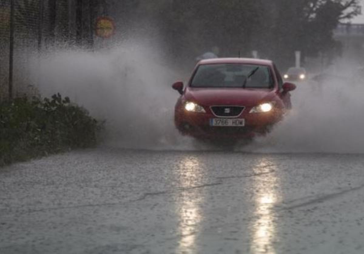 Un vehículo se abre paso en mitad de una calle inundada por el agua.