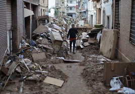 Un hombre intenta limpiar una calle en Paiporta.