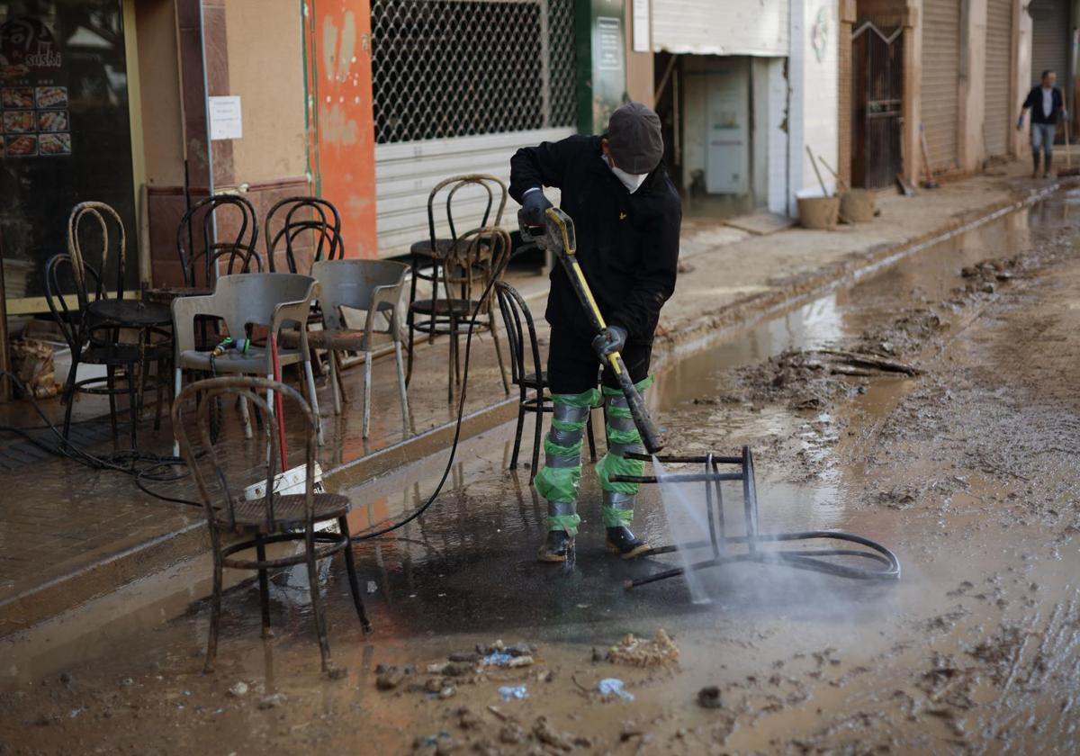 Un voluntario limpia las sillas de un bar de Catarroja.