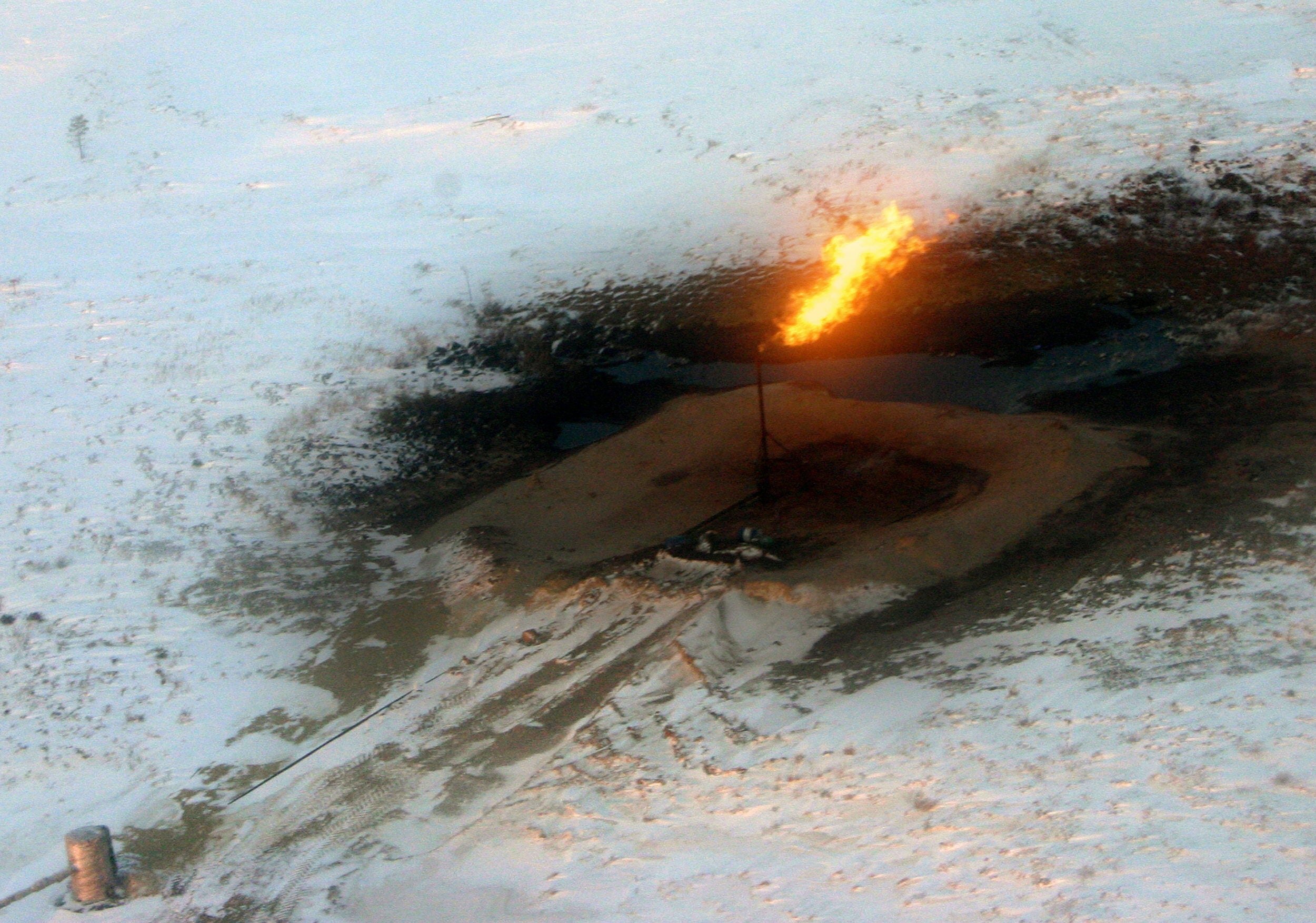 Chimenea exhala fuego en las instalaciones de una refinería de petróleo, en Nadym (Siberia), rodeada de una capa de nieve.