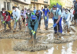 Un grupo de jóvenes voluntarios retira el barro de una calle de Paiporta, la 'zona cero' de la catástrofe.