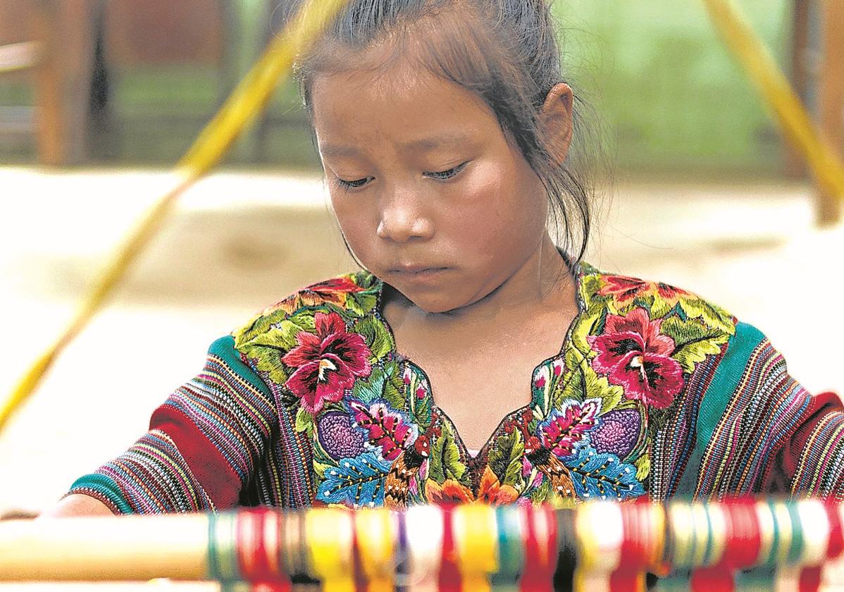 Una niña trabaja en un tapiz.