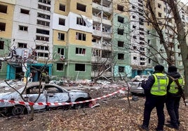 Dos agentes de policía observan los daños causados por un misil ruso en un edificio de la ciudad de Sumi.